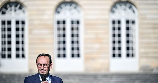 Un orateur s’adressant à la presse devant un bâtiment administratif.
