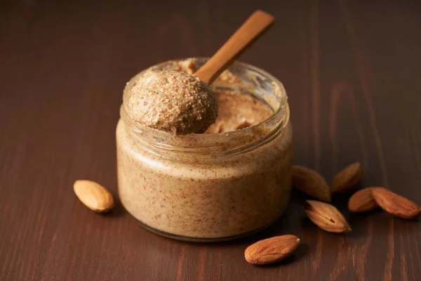 Beurre d'amande maison préparé à partir d'un produit Aldi, avec amandes et cuillère en bois.