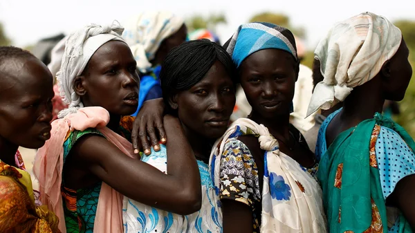 Des femmes sud-soudanaises vêtues de tenues colorées se réconfortent mutuellement dans un camp de déplacés.
