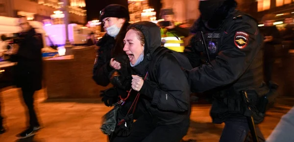 Des policiers russes interpellent une manifestante antiguerre lors d'une opération de répression nocturne.