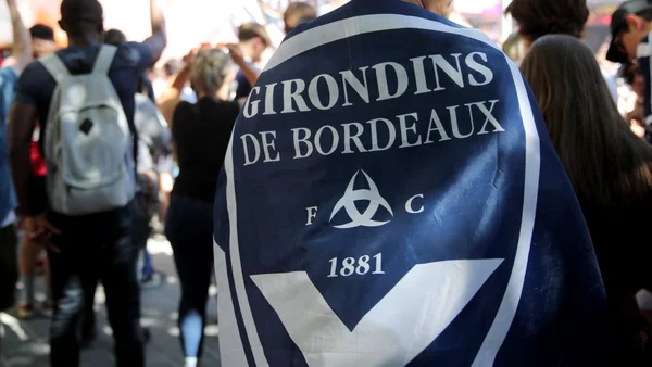 Un supporter des Girondins de Bordeaux brandissant un drapeau aux couleurs du club dans une foule.