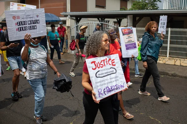 Manifestation avec des pancartes exigeant justice et soins pour les victimes du chlordécone.