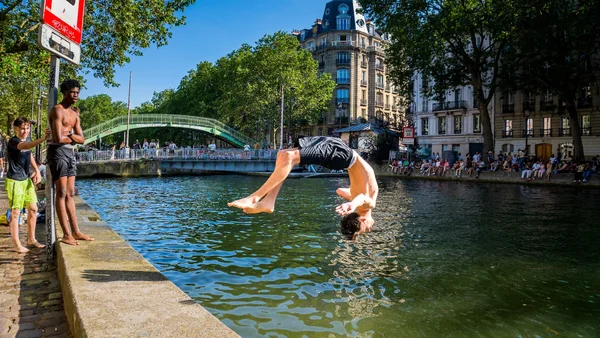 Un jeune homme plonge dans le canal Saint-Martin sous le regard de deux amis.