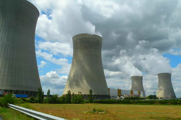 Quatre tours de refroidissement d'une centrale nucléaire rejetant de la vapeur.