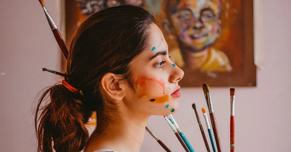 Portrait d'une artiste rouennaise avec des traces de peinture et des pinceaux, illustrant la mobilisation des illustrateurs locaux.