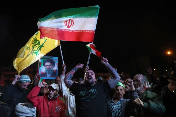 Rassemblement de manifestants en Iran avec drapeaux et portrait religieux.
