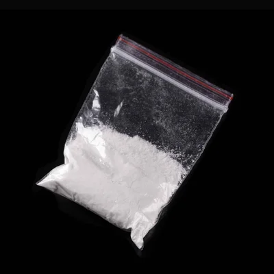 Sachet de 3-MMC, drogue de synthèse, présenté sur fond noir.
