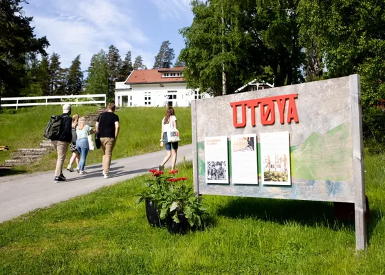 Des visiteurs se rendent sur l'île d'Utøya, passant devant le panneau emblématique.