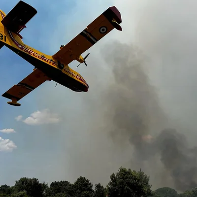 Un Canadair de la Sécurité civile survolant un incendie dégageant une épaisse fumée.