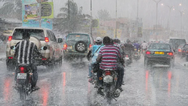 Des motocyclistes et automobilistes tentent de circuler sous une pluie diluvienne dans les rues inondées de Lomé.
