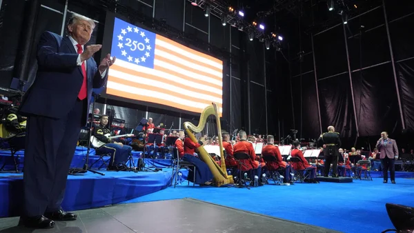 Donald Trump sur scène, s'adressant à un orchestre militaire lors du lancement des célébrations du 250e anniversaire.
