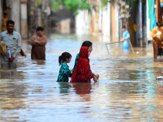 Des habitants déplacés dans une rue inondée, illustrant les inondations, un des aléas climatiques affectant les enfants.
