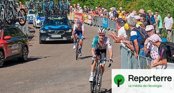 Deux coureurs du Tour de France en pleine compétition, entourés de supporters et de voitures d'équipe.