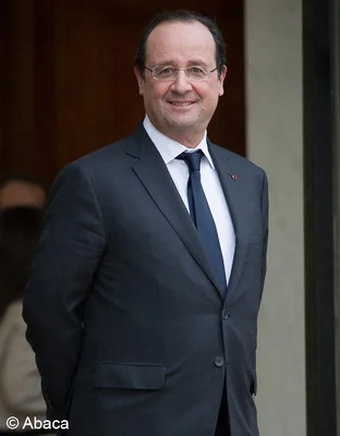 Portrait de François Hollande souriant, en costume-cravate.