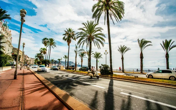 La Promenade des Anglais à Nice, avec palmiers et circulation sous un ciel bleu.