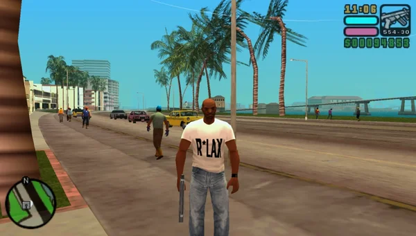 Capture d'écran du jeu vidéo Grand Theft Auto: Vice City Stories (2006), montrant le personnage principal, Victor Vance, marchant dans les rues de Vice City. L'image illustre l'environnement tropical et urbain caractéristique du jeu, avec des palmiers, des voitures et une interface utilisateur typique de la série GTA.