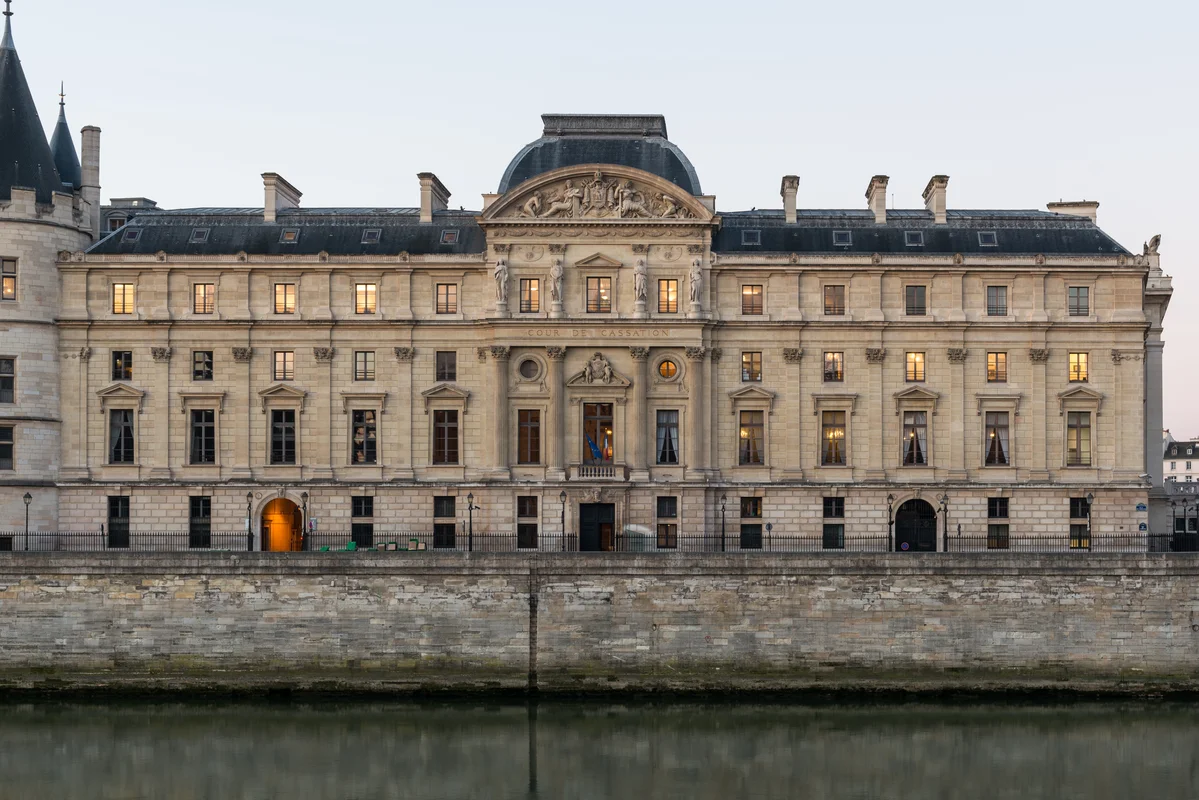 Silhouette devant la Cour de cassation sous un ciel sombre