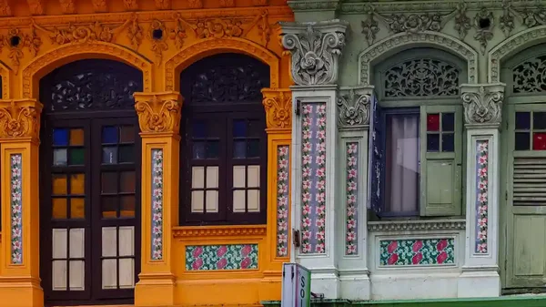 Close up of colorful Peranakan architectural tiles and wooden shutters.