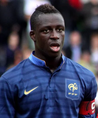 Benjamin Mendy en maillot bleu de l'équipe de France avec le logo FFF et Nike, portant un brassard de capitaine rouge au bras gauche.