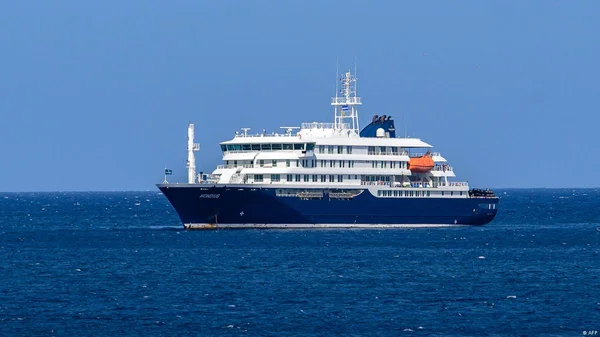 Un grand navire de croisière bleu et blanc nommé 'NOMADIS' naviguant sur une mer calme et bleue sous un ciel dégagé, illustrant un autre navire lié à la gestion du foyer d'hantavirus aux Canaries.