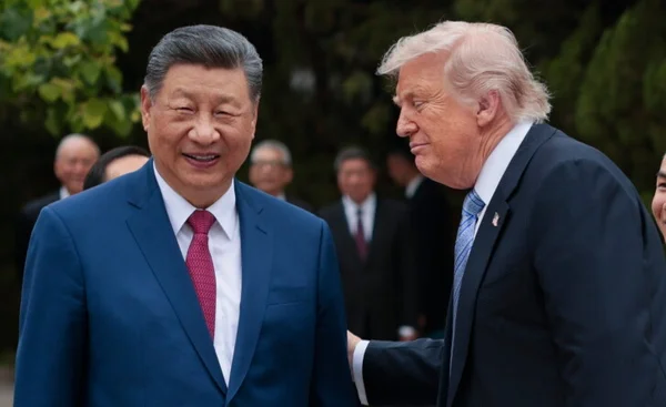 Donald Trump et Xi Jinping, tous deux en costume, marchant et discutant en plein air lors d'un sommet, avec d'autres responsables en arrière-plan flou.