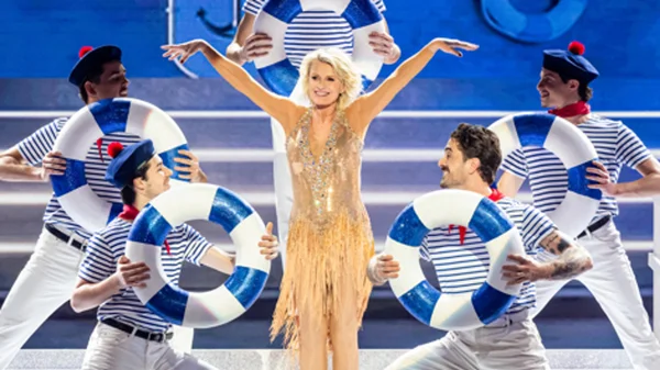 Sophie Davant en robe dorée à franges et paillettes sur la scène de Danse avec les stars 2025, entourée de danseurs en marinière tenant des bouées, chorégraphie sur "Mama Mia" d'Abba.