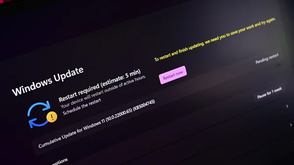 Capture d'écran d'un moniteur d'ordinateur affichant l'écran de Windows Update demandant un redémarrage pour finaliser l'installation d'une mise à jour cumulative de Windows 11, avec un éclairage tamisé et un angle rapproché.