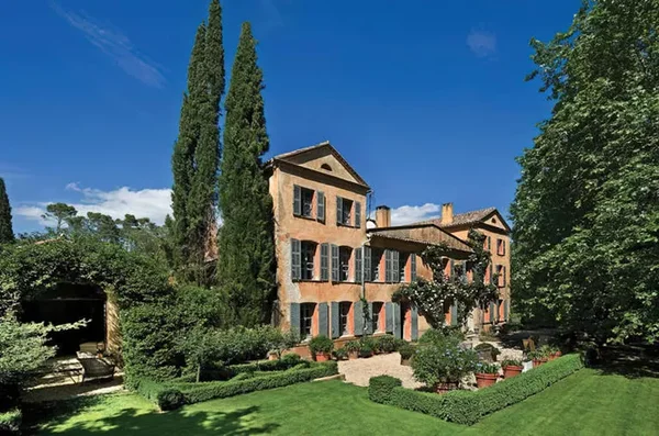 Le domaine de Canadel, villa ocre à deux étages aux volets verts, entourée de jardins luxuriants et de cyprès sous un ciel bleu clair