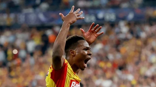Mamadou Sangaré, joueur du RC Lens, célèbre en levant les bras et en criant de joie, vêtu du maillot rouge et jaune, devant un public en arrière-plan flou lors de la finale de la Coupe de France contre l'OGC Nice au Stade de France.