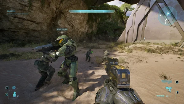 Capture d'écran de gameplay de Halo Infinite montrant le Master Chief et des soldats dans un environnement désertique, avec un pistolet et un HUD affichant objectifs et radar