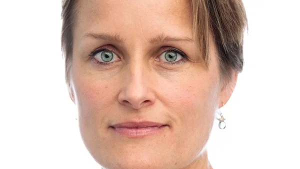 Portrait en gros plan de Blaise Metreweli, future première femme à la tête du MI6, regardant l'objectif avec des cheveux blonds courts et les yeux bleus, sur fond blanc.