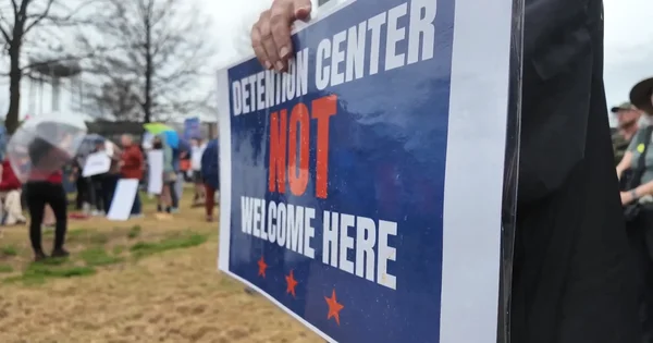Manifestant tenant une pancarte 'DETENTION CENTER NOT WELCOME HERE' lors d'un rassemblement à Walton County contre le centre de détention ICE proposé à Social Circle, en Géorgie.