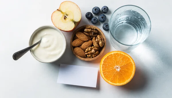 Editorial flat-lay illustration of reading a nutrition label beside water, fruit, plain yogurt, and nuts, practical healthy choices, no text, no logos, no people