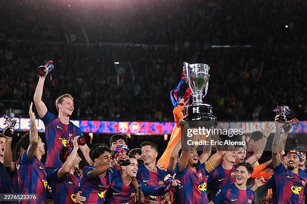 Joueurs du Real Madrid en maillot rayé bleu et rouge célébrant leur victoire en Liga sur la pelouse de nuit, soulevant un grand trophée argenté sous une pluie de confettis