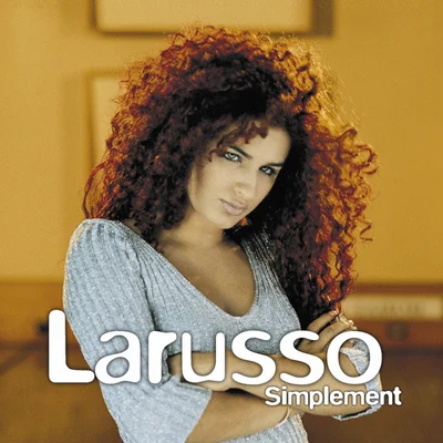 Pochette de l'album 'Simplement' de Larusso, montrant la chanteuse aux cheveux bouclés roux et yeux bleus, portant un haut gris côtelé, avec le titre 'Larusso' et 'Simplement' superposés.