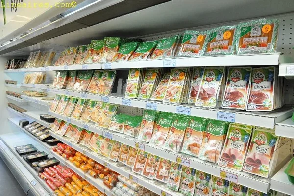 Rayon réfrigéré d'un supermarché avec diverses charcuteries et saucisses emballées, dont du chorizo et du bœuf, sous un éclairage fluorescent.