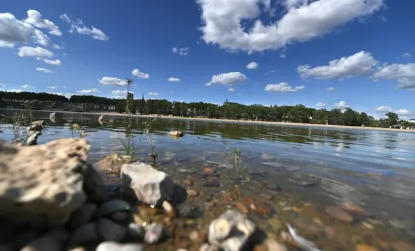Photographie en contre-plongée de la Loire à Orléans (Loiret) montrant des bancs de sable exondés et des galets visibles dans une eau claire, sous un ciel bleu avec quelques nuages, illustrant l'étiage saisonnier du fleuve.