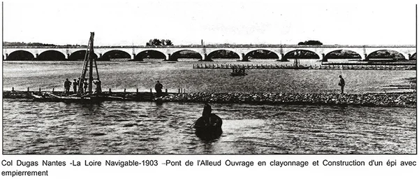 Photographie historique en noir et blanc de 1903 montrant des ouvriers construisant une structure en fascines et un remblai en pierre sur la Loire près de Nantes, avec un pont à arches en arrière-plan.