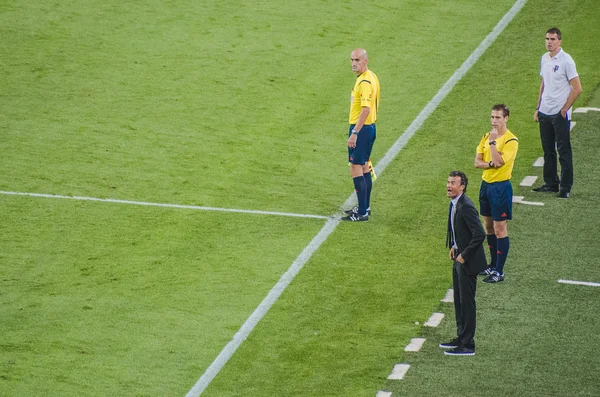 Luis Enrique, entraîneur du FC Barcelone, en costume, criant des instructions depuis la touche lors d'un match contre Eibar en 2014, entouré d'arbitres en maillots jaunes.