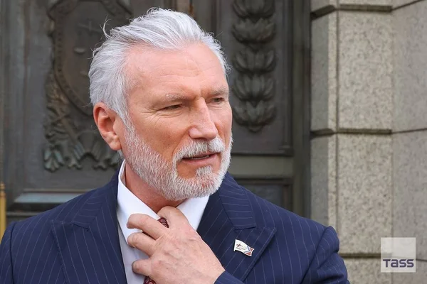 Portrait du député russe Alexeï Jouravlev, président du parti Rodina, en costume bleu marine à fines rayures, ajustant sa cravate, avec le filigrane TASS