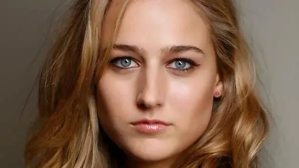 Portrait en gros plan de Leelee Sobieski, jeune actrice blonde aux yeux bleus, regardant l'objectif sur fond gris neutre.