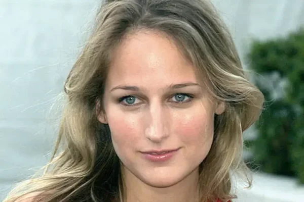 Portrait en gros plan de Leelee Sobieski, blonde aux yeux bleus, regardant l'objectif, avec un arrière-plan flou de verdure et une surface claire.