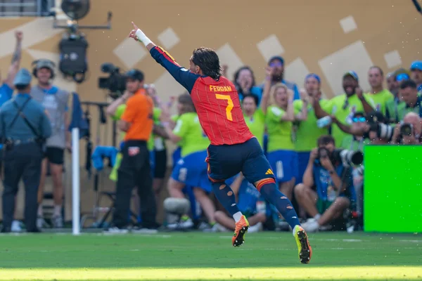 Ferran Torres célèbre son but lors de la finale de la Coupe du Monde 2026 entre l'Argentine et l'Espagne, portant le maillot rouge et bleu de l'Espagne avec le numéro 7, pointant le ciel dans un stade ensoleillé.