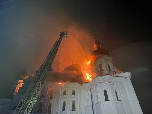 La cathédrale de la Dormition en proie aux flammes la nuit, une échelle de pompier déployée vers le toit pour arroser le bâtiment en feu.