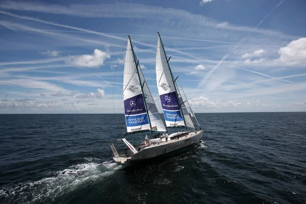Le voilier Pangaea de Mike Horn, avec les logos Mercedes-Benz et Officine Panerai, naviguant en pleine mer sous un ciel bleu.