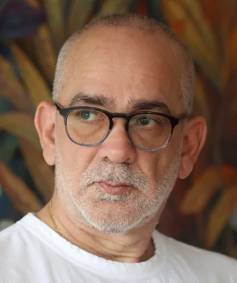 Portrait de Gustavo Faverón Patriau, écrivain péruvien, avec des cheveux grisonnants, une barbe poivre et sel et des lunettes à monture noire, portant un t-shirt blanc, lors du Festival Hispanoamericano de Literatura.