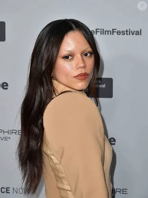 Jenna Ortega, en haut à la première du film The Gallerist au Festival du Film de Sundance 2026, regardant par-dessus son épaule, maquillage glamour et haut beige.