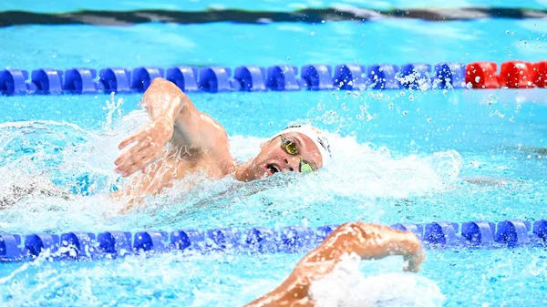 Léon Marchand, nageur français, célébrant sa qualification pour la finale du 400 m nage libre aux Championnats d'Europe de natation, dans son maillot de bain, au bord du bassin.