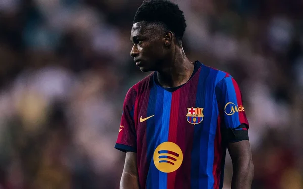 Jesse Bisiwu, 18 ans, prodige camerounais, lors de ses débuts avec le FC Barcelone : il porte le maillot rayé bleu et grenat et regarde sur le côté, l'air sérieux et déterminé.