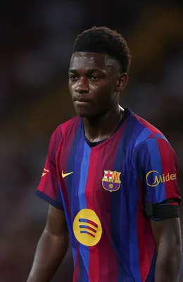 Jesse Bisiwu, jeune joueur du FC Barcelone, en maillot blaugrana avec les sponsors Spotify et Midea, regardant sur le côté avec une expression sérieuse.